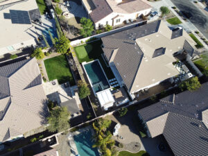 Thumbnail of http://Aerial%20view%20of%20a%20residential%20neighborhood%20in%20Arizona%20showing%20a%20contemporary%20home%20with%20a%20narrow%20rectangular%20pool,%20travertine%20deck,%20artificial%20turf%20lawn%20and%20neighboring%20houses,%20captured%20by%20Phoenix%20pool%20builders.