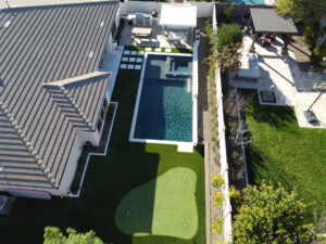 Thumbnail of http://Aerial%20view%20of%20a%20Phoenix%20home%20with%20a%20modern%20backyard%20featuring%20a%20rectangular%20pool,%20raised%20spa,%20artificial%20turf%20patterns%20and%20paver%20walkways%20designed%20by%20pool%20builders.