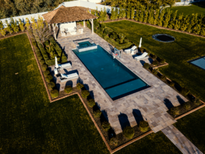 Bird's-eye view of modern lap pool with attached spa and separate square lounge pool surrounded by travertine patio in Glendale Arizona built by Caribbean Pools