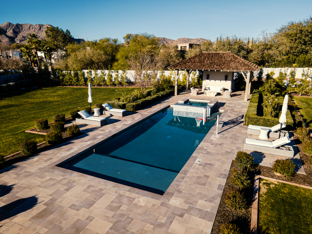 Drone photo of a long rectangular lap pool with travertine deck, cabana and desert landscape in Scottsdale Arizona built by Caribbean Pools