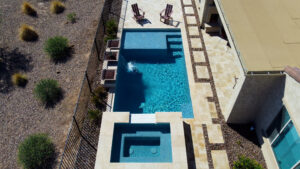 Thumbnail of http://Drone%20view%20of%20sleek%20rectangular%20lap%20pool%20with%20adjacent%20elevated%20spa%20and%20travertine%20deck,%20bordered%20by%20desert%20landscaping%20in%20Scottsdale%20Arizona%20built%20by%20Caribbean%20Pools