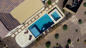 Thumbnail of http://Aerial%20oblique%20view%20of%20modern%20rectangular%20pool%20with%20steps,%20raised%20square%20spa%20and%20travertine%20patio%20at%20luxury%20home%20in%20Phoenix%20Arizona%20built%20by%20Caribbean%20Pools