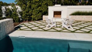 Poolside seating area with fireplace and grass paver patio in Chandler Arizona